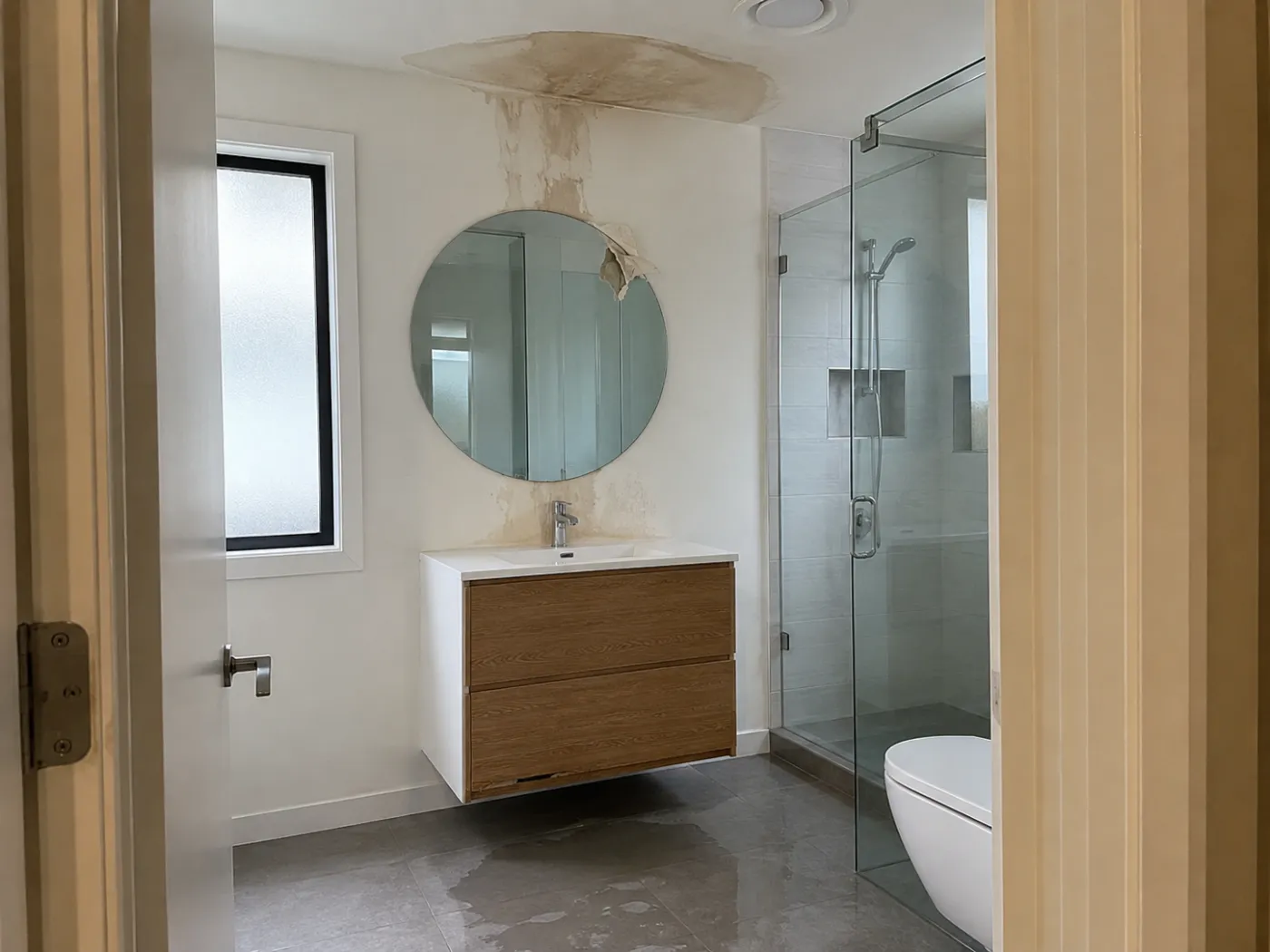 Bad mit Wasserfleck an der Decke über dem Waschtisch, Wasser auf den Bodenfliesen (KI-generiertes Beispielbild)